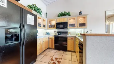 a kitchen with wooden cabinets and a black refrigerator at Mammoth West #137 Condo in Mammoth Lakes