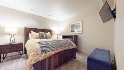 a bedroom with a large bed with a blue ottoman at Mammoth West #137 Condo in Mammoth Lakes