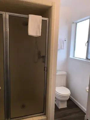 a bathroom with a shower with a toilet and a window at Cedar Inn & Suites in South Lake Tahoe