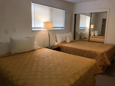 a hotel room with two beds and a mirror at Cedar Inn & Suites in South Lake Tahoe