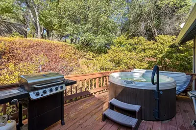 a hot tub and a grill on a deck at Yosemite Falls Calling in Groveland
