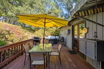 a table with a yellow umbrella on a deck at Yosemite Falls Calling in Groveland