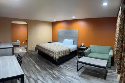 a hotel room with a bed and a chair at Apex Inn in Modesto