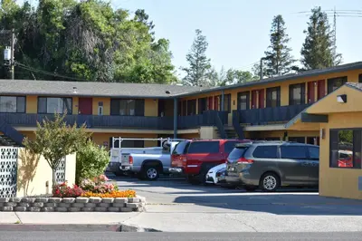 a hotel with cars parked in a parking lot at Apex Inn in Modesto