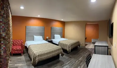 a hotel room with two beds and a chair at Apex Inn in Modesto