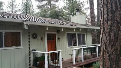 a small house with a porch next to a tree at Lovely Mountain Lake Chalet by Yosemite: Equipped! in Groveland