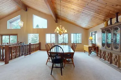 a dining room with a table and chairs and windows at House on Cold Creek in South Lake Tahoe