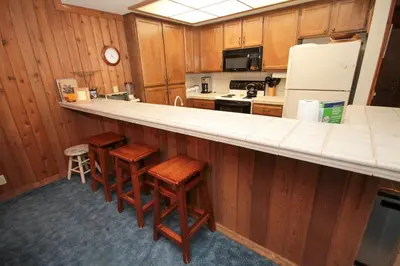 a kitchen with wooden cabinets and a counter with stools at Mountainback 45 Den in Mammoth Lakes
