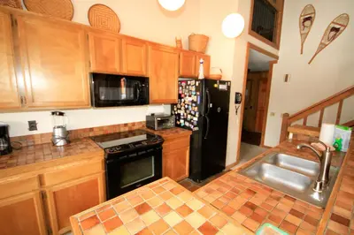 a kitchen with wooden cabinets and a black refrigerator at Mountainback 40 Loft Corner in Mammoth Lakes