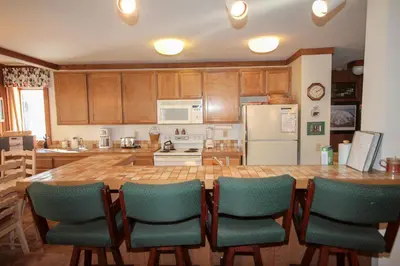 a kitchen with a large wooden table and green chairs at Mountainback 34 Corner in Mammoth Lakes
