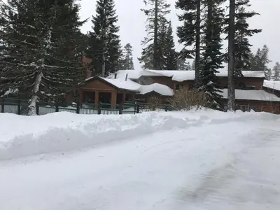 a house covered in snow in front of a yard at Mountainback 34 Corner in Mammoth Lakes
