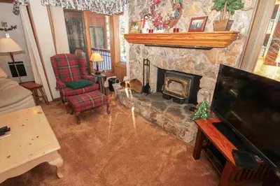 a living room with a stone fireplace and a tv at Mountainback 34 Corner in Mammoth Lakes