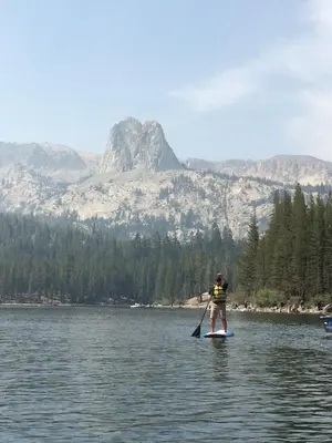 a man riding a paddle board on a lake at Mammoth Ski Racquet Club 64 - Pet Friendly in Mammoth Lakes