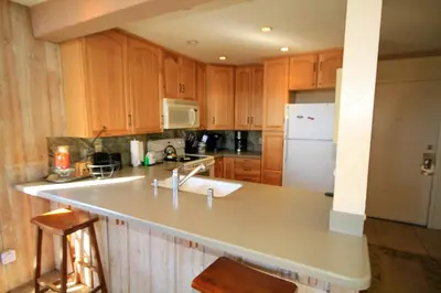a kitchen with wooden cabinets and a white refrigerator at Mammoth Ski Racquet Club 64 - Pet Friendly in Mammoth Lakes