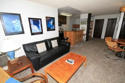 a living room with a black leather couch and a table at Crestview 17 in Mammoth Lakes