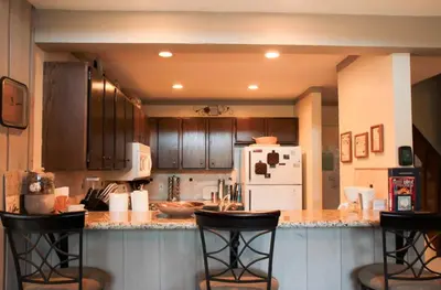 a kitchen with wooden cabinets and bar stools at Mammoth Ski & Racquet Club #84 in Mammoth Lakes