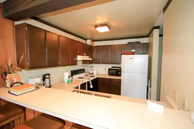 a kitchen with wooden cabinets and a white refrigerator at Mammoth Ski Racquet Club 129 in Mammoth Lakes