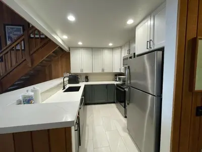 a kitchen with white cabinets and a stainless steel refrigerator at Mountainback 115 3 bedroom loft in Mammoth Lakes