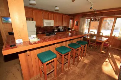 a kitchen with a bar with green cushioned stools at Mountainback 112 Corner Unit in Mammoth Lakes