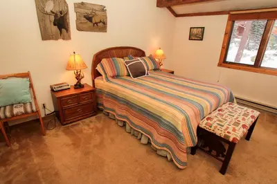 a bedroom with a bed and a chair and a window at Mountainback 105 Loft Den in Mammoth Lakes