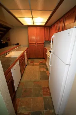 a kitchen with a white refrigerator and a tile floor at Mountainback 97 Loft in Mammoth Lakes