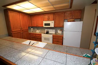 a kitchen with wooden cabinets and a white refrigerator at Mountainback 97 Loft in Mammoth Lakes