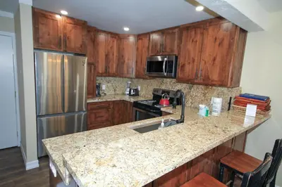 a kitchen with wooden cabinets and a granite counter top at Mammoth Ski Racquet Club 12 - Pet Friendly in Mammoth Lakes