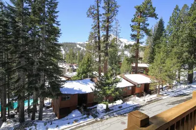 a view from the deck of a resort with snow covered trees at Mammoth Ski Racquet Club 12 - Pet Friendly in Mammoth Lakes