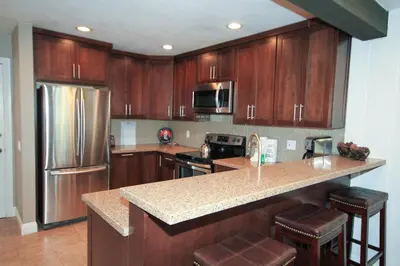 a kitchen with wooden cabinets and a stainless steel refrigerator at Mammoth Ski Racquet Club 38 - Pet ok - Loft in Mammoth Lakes