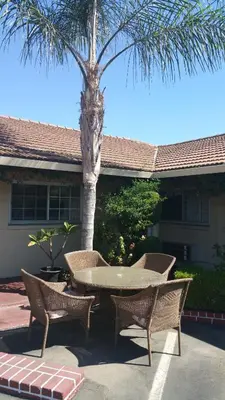 a patio with a table and chairs and a palm tree at San Joaquin Motel in Merced