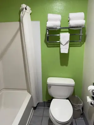 a green bathroom with a toilet and towels at Hollister Inn in Hollister