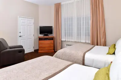 a hotel room with two beds and a flat screen tv at Candlewood Suites Turlock by IHG in Turlock