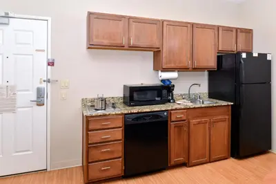 a kitchen with wooden cabinets and a black refrigerator at Candlewood Suites Turlock by IHG in Turlock