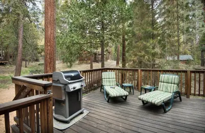 a grill and chairs on a deck with trees at 16 Chipmunks Holiday in Wawona