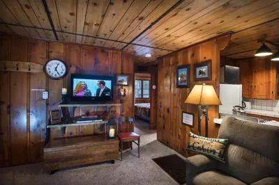 a living room with a clock on a wooden wall at 16 Chipmunks Holiday in Wawona