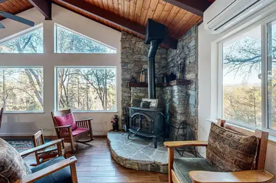a living room with a stone fireplace and windows at Pine Mountain Magic in Groveland