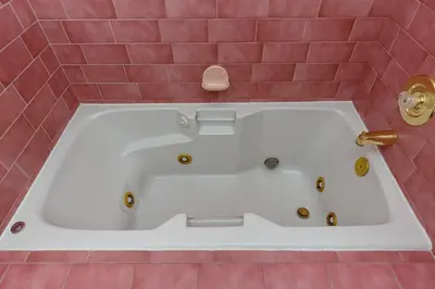 a bath tub in a pink tiled bathroom at Miners Inn in Mariposa
