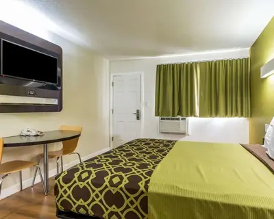 a small hotel room with a bed and a table and a television at Rodeway Inn Downtown Hanford in Hanford