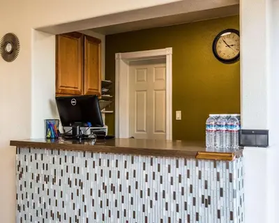 a kitchen with a counter with a clock on the wall at Rodeway Inn Downtown Hanford in Hanford