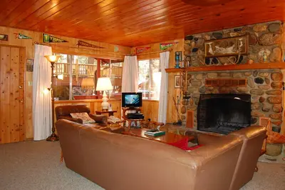 a living room with a couch and a stone fireplace at 28 Raccoon's End in Wawona