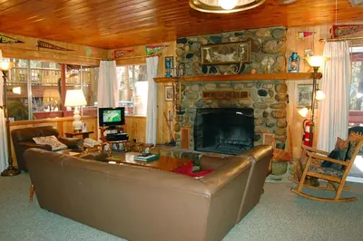 a living room with a couch and a stone fireplace at 28 Raccoon's End in Wawona