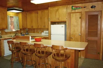 a kitchen with wooden cabinets and a island with bar stools at 28 Raccoon's End in Wawona