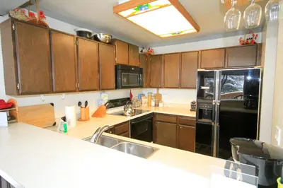 a kitchen with wooden cabinets and a black refrigerator at Mammoth Ski Racquet Club 74 1 Bdrm Loft in Mammoth Lakes