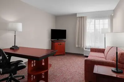 a hotel room with a desk and a couch and a television at Larkspur Landing Extended Stay Suites Roseville in Roseville