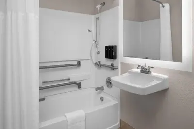 a white bathroom with a sink and a bath tub at Larkspur Landing Extended Stay Suites Roseville in Roseville