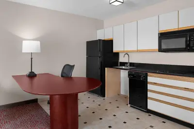 a kitchen with a table and a black refrigerator at Larkspur Landing Extended Stay Suites Sacramento in Sacramento