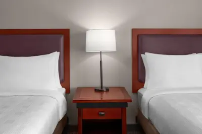 a bedroom with two beds and a table with a lamp at Larkspur Landing Extended Stay Suites Folsom in Folsom