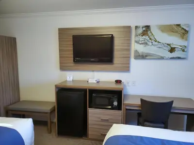 a hotel room with a tv and a desk with a chair at Exchange Club Motel in Beatty