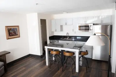a kitchen with white cabinets and a kitchen island with stools at Carson Valley Motor Lodge and Suites in Minden