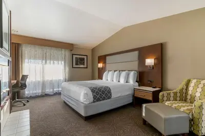 a hotel room with a bed and a chair at Best Western Plus Forest Park Inn in Gilroy